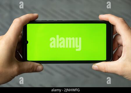 téléphone mobile avec touche verte chroma sur écran tactile entre les mains de la femme... Banque D'Images
