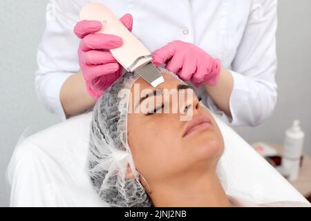 Médecin de beauté avec scabre ultrasonique faisant la procédure de nettoyage ultrasonique du visage. Cosmétologie et soin du visage. Banque D'Images