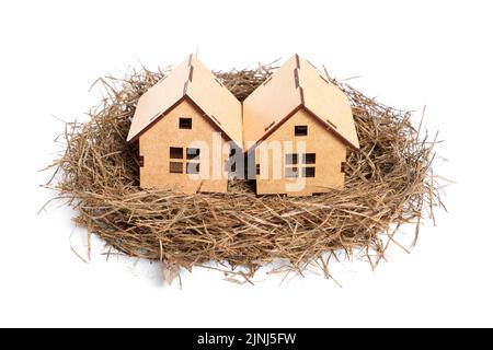 Deux petits modèles de maison en bois dans un nid d'oiseau isolé sur blanc. Concept de maison douce. Banque D'Images