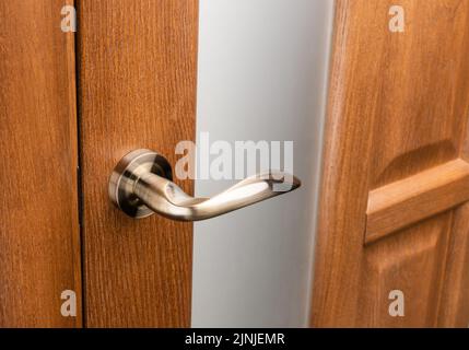 Poignée de porte extérieure sans serrure de protection sur cadre en bois. Gros plan de la poignée de porte métallique sur la porte avant ou intérieure marron. Design de porte de maison choic Banque D'Images