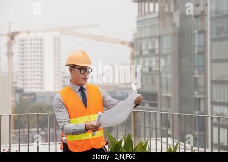 Un jeune ingénieur civil professionnel examine le plan dans ses mains Banque D'Images