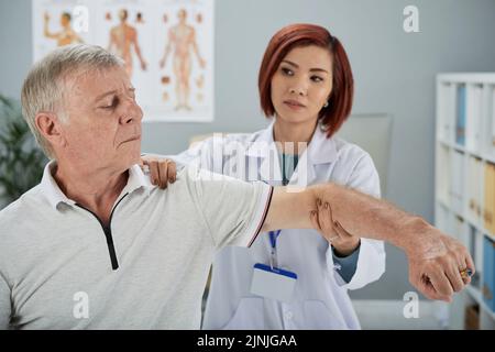 Jeune travailleuse de centre de réadaptation travaillant avec le patient Banque D'Images