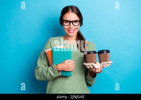 Photo de gaie bras de dame tenir le livre deux tasse café délicieux sourire isolé sur fond bleu de couleur Banque D'Images