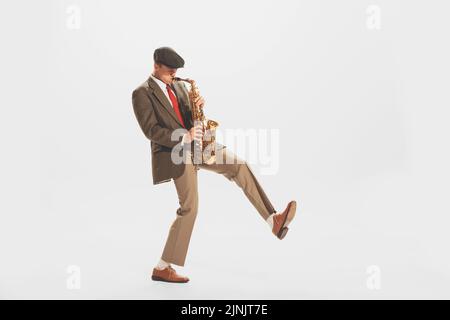 Portrait d'un jeune homme élégant jouant de la trompette isolé sur fond blanc de studio. Mode de vie musical, passe-temps Banque D'Images