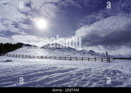 Paysage enneigé de haute montagne avec rayons du soleil et ciel avec nuages. Banque D'Images