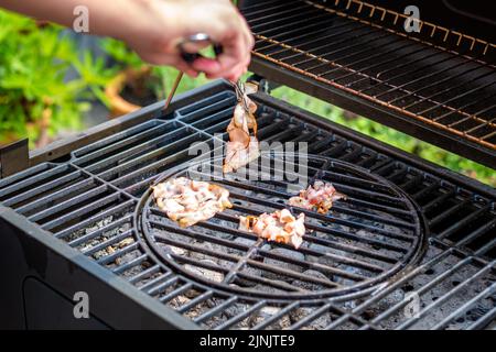 Cuisson du bacon sur le gril chaud, préparation d'aliments malsains. Banque D'Images