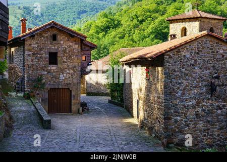 Anciennes maisons en pierre et tour d'église catholique dans le village de montagne. Le maire de Barcena. Banque D'Images