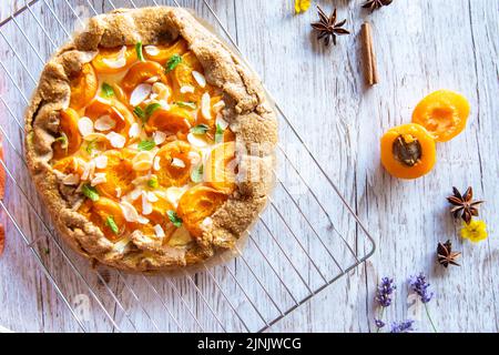 Gâteau à tarte à la galette d'abricot placé sur fond de bois avec des outils de cuisson sur le côté Banque D'Images