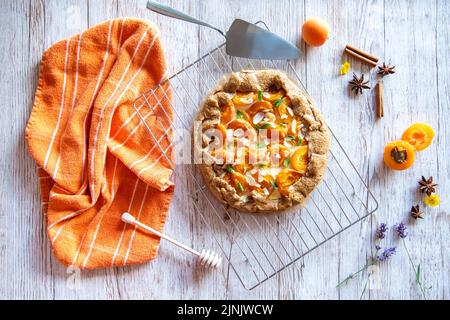 Gâteau à tarte à la galette d'abricot placé sur fond de bois avec des outils de cuisson sur le côté Banque D'Images