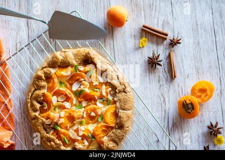 Gâteau à tarte à la galette d'abricot placé sur fond de bois avec des outils de cuisson sur le côté Banque D'Images