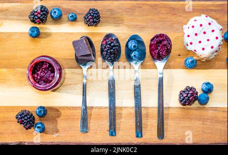 Le bleuet, le mûre et le chocolat sont placés dans une cuillère en argent sur un bureau en bois. Ingrédients pour la marmelade. Fruits frais. Banque D'Images