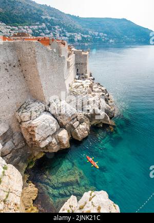 Vue depuis les falaises rocheuses de la kayakiste explorer les eaux limpides de la Méditerranée d'une anse de la côte de Dubrovnik, Croatie Banque D'Images