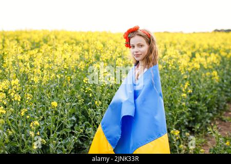 Priez pour l'Ukraine. Enfant avec drapeau ukrainien dans champ de colza. Fille tenant le drapeau national priant pour la paix. Banque D'Images