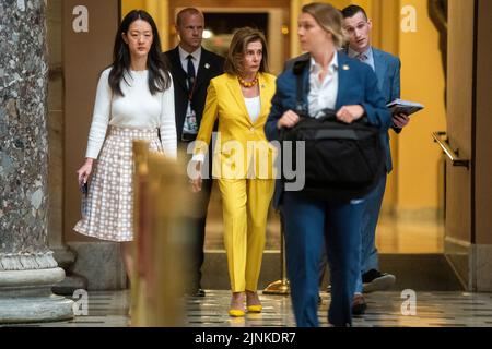 La Présidente de la Chambre Nancy Pelosi s'entretient avec les membres du personnel alors qu'elle traverse la statuaire Hall du Capitole des États-Unis à Washington, DC, USA, le 12 août 2022. Les Démocrates de la Chambre des représentants poursuivent leur travail pour adopter la Loi sur la réduction de l'inflation, un projet de loi de dépenses important qui comprend des dispositions sur le changement climatique, les soins de santé et les augmentations de l'impôt sur les sociétés. Banque D'Images