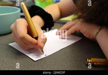 Mains d'une jeune femme qui utilise un stylo à plume Banque D'Images