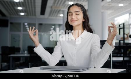 Jeune femme fatiguée employée de bureau travaillant sur ordinateur portable dactylographie rapport termine le travail calme équilibrée femme gestionnaire médite avec les yeux fermés se reposant à Banque D'Images