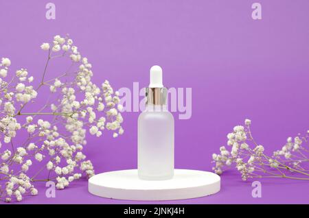 Bouteille cosmétique avec compte-gouttes sur un podium blanc avec un bouquet de gitsophila. Cosmétiques pour les soins de la peau Banque D'Images