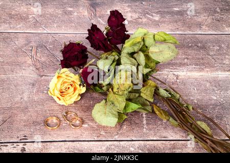 Fleurs de rose sauvages mortes et mariage et un anneau d'engagement sur une table en bois Banque D'Images