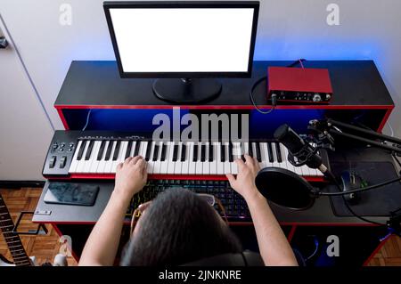 Vue de dessus de la personne assise dans le studio de musique de maison ensemble jouant l'enregistrement de piano, la composition et la production de musique, regardant l'écran d'ordinateur. Banque D'Images