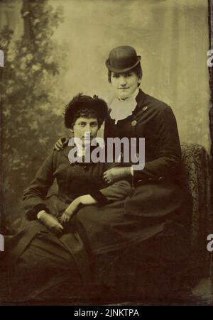 Studio victorien noir et blanc photo portrait de deux femmes portant une tenue du milieu à la fin du XIXe siècle vers 1870s Banque D'Images