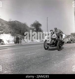 1960, historique, de Londres à Brighton course de voiture vétéran, sur le chemin Brighton (A23) deux hommes à bord d'un véhicule à trois roues à toit ouvert, un tricycle à moteur (numéro P 408)... espérons que le monsieur assis à l'avant est attaché en ...no casques crash dans ces jours-là Bien sûr. Pour participer à la course de voiture de vétéran, tous les véhicules à moteur doivent être PRRE 1905. Une Ford 100E de l'époque vue sur la route derrière. Banque D'Images