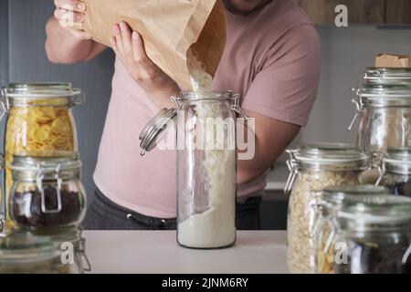 latins méconnaissables remplissant un pot de farine de blé dans un sac en papier. Banque D'Images