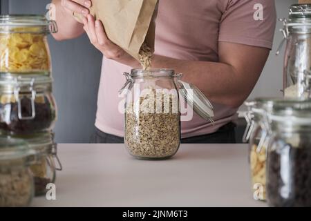 latins méconnaissables remplissant un pot de flocons d'avoine d'un sac en papier. Banque D'Images