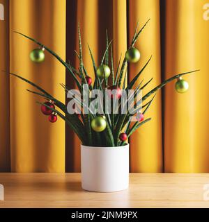 Composition de Noël carré. Plante maison verte décorée de boules de Noël contre des rideaux jaunes, vue de face. Banque D'Images