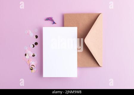 Carte vide avec confettis, enveloppe et dauphin de lavande décoratif sur fond de lilas pastel. Flat Lay avec espace vide pour votre conception. Banque D'Images