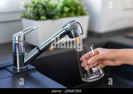 Remplir un verre d'eau potable du robinet de la cuisine Banque D'Images