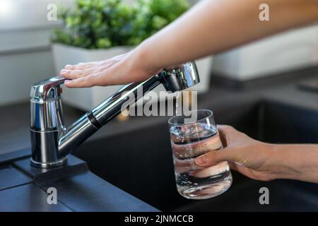 La main de la femme éteint le robinet dans la cuisine. Banque D'Images