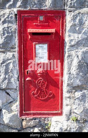 Une boîte postale montée sur un mur en pierre avec des informations bilingues en anglais et en gallois, située à Rhos sur Sea North Wales, au Royaume-Uni Banque D'Images