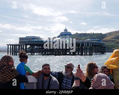 Llandudno, Clwyd, pays de Galles, 07 août 2022: Les gens qui profitent d'un voyage en bateau avec la jetée en arrière-plan. Banque D'Images
