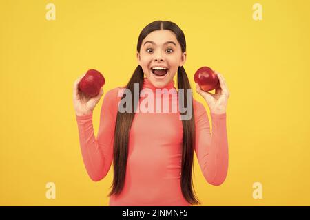 enfant surpris avec une pomme rouge sur fond jaune, en régime Banque D'Images