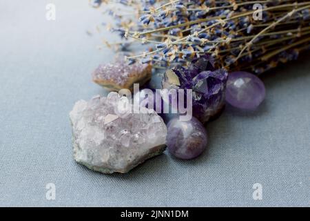 Belles pierres améthystes et druze améthyste avec un bouquet de lavande sec sur un tissu en coton. Amulettes magiques. Banque D'Images