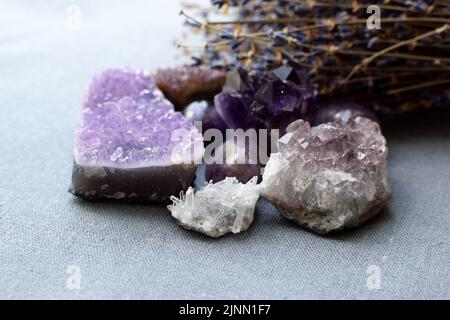 Belles pierres améthystes et druze améthyste avec un bouquet de lavande sec sur un tissu en coton. Amulettes magiques. Banque D'Images