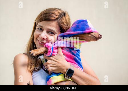 Femme latine tenant son chien vêtu de la même façon. Elle regarde la caméra Banque D'Images