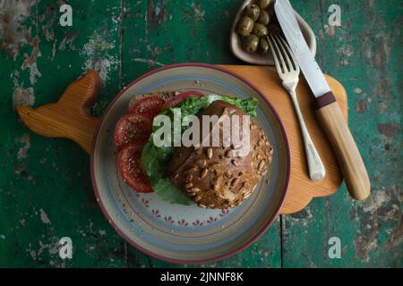 Rouleau de graines de tournesol avec tomates et olives sur bois Banque D'Images
