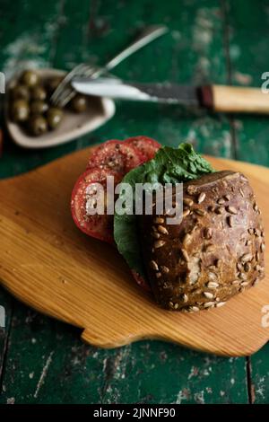 Rouleau de graines de tournesol avec tomates et olives sur bois Banque D'Images