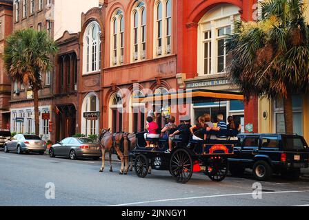 Un groupe de touristes apprécient une lente promenade en calèche des sites historiques et des bâtiments de la charmante ville de Charleston, en Caroline du Sud Banque D'Images