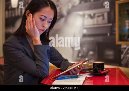 Jeune femme asiatique avec iPad et capuchino dans un café, Tokyo, Japon Banque D'Images