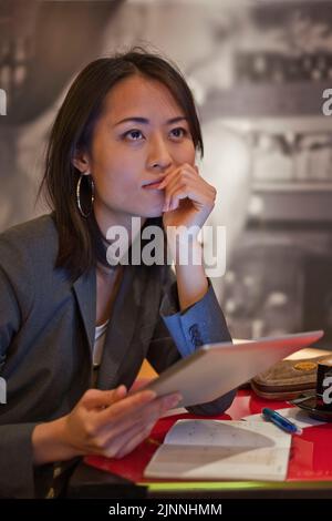 Jeune femme asiatique avec iPad et capuchino dans un café, Tokyo, Japon Banque D'Images