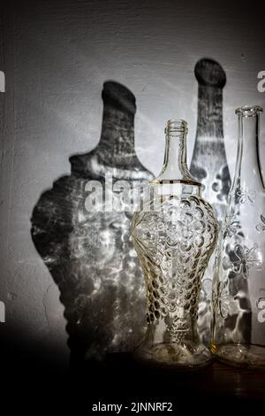 Deux bouteilles millésimes transparentes et une ombre abstraite de celles-ci sur le mur Banque D'Images