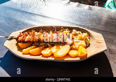 Brochette de porc grillée côtelettes pommes de terre choux plaque en bois.ils sont sur la table à l'extérieur.gros plan. Banque D'Images