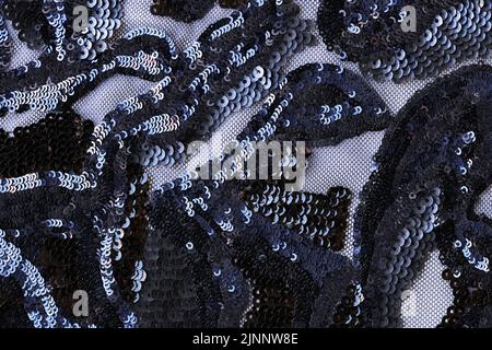 Tissu noir transparent orné de fleurs en sequins sur fond texturé Banque D'Images