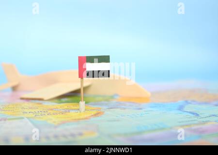 Mise au point sélective du drapeau des Émirats arabes Unis sur une carte du monde floue et un modèle d'avion en bois. Les Émirats arabes Unis comme concept de voyage et de destination touristique. Banque D'Images