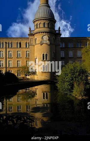 Un reflet calme de l'industrie de la laine des Cotswolds et de son patrimoine à Chipping Norton, Oxfordshire, Angleterre, Royaume-Uni: La façade majestueuse et la tour de cheminée de l'ancien moulin Bliss Tweed, se reflète dans un lac paisible au milieu des jardins paysagers. La tour, surmontée d’un dôme nervuré, porte la date de construction de l’usine en 1872. Il a fermé ses portes en 1980 et a depuis été converti en appartements de luxe. Banque D'Images