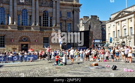 Édimbourg, Écosse, 11 août, 2022 Festival Fringe une foule de gens regardant une jeune dame se balancer sur une table avec un hula hoop tournant sur chaque bras Banque D'Images