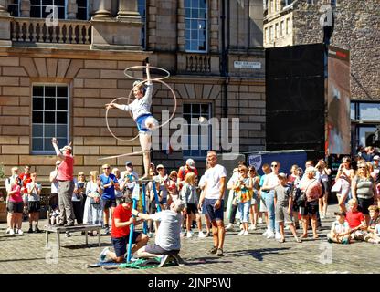 Édimbourg, Écosse, 11 août, 2022 Festival Fringe les gens qui regardent une jeune dame se balançant sur une table avec un hula hoop tournant sur chaque bras et jambe Banque D'Images