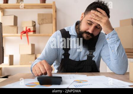 Entrepreneur indien faisant l'analyse des coûts pour la petite entreprise, comptable faisant de la paperasserie. Calcul des revenus et des dépenses calculatrice. Homme Banque D'Images